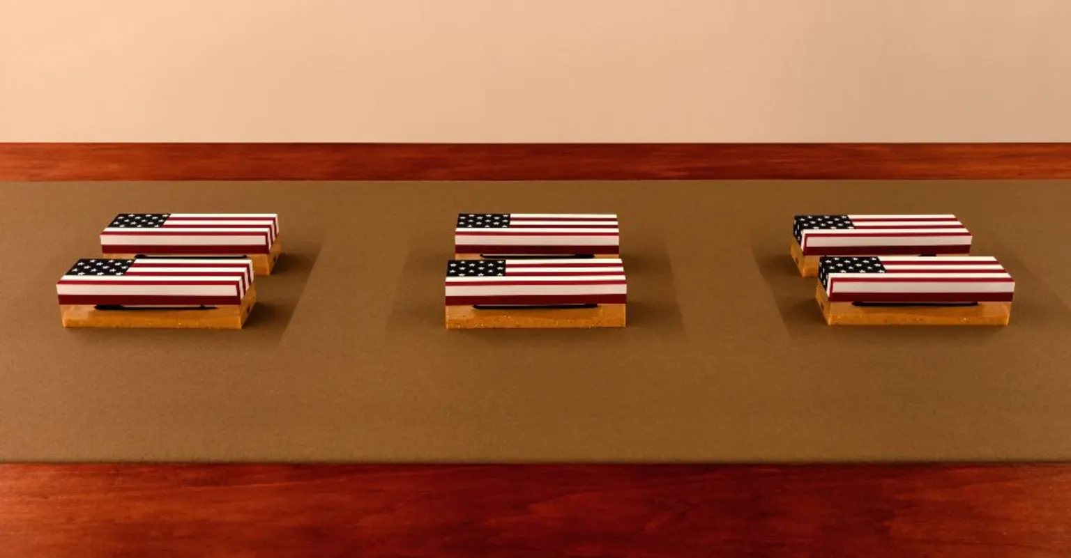 Jack Elliot Edwards Small objects featuring coffins draped in the American flag from Tanoa Sasraku's Morale Patch installation at the Institute of Contemporary Arts, London