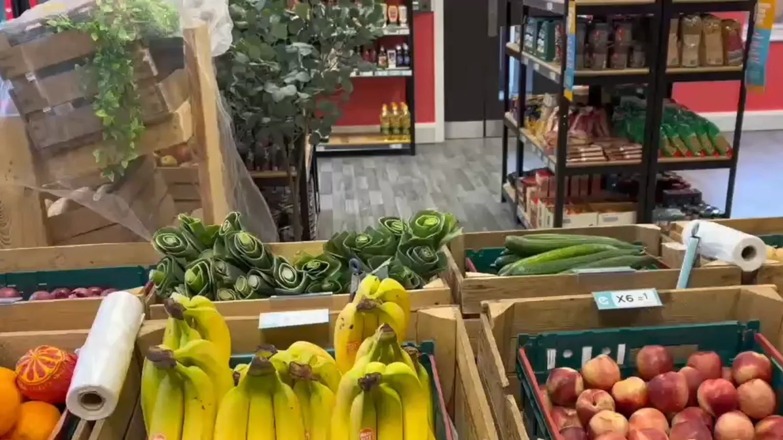 Clare Dutton/BBC A shop with baskets of fruit and vegetables lined up in the foreground.