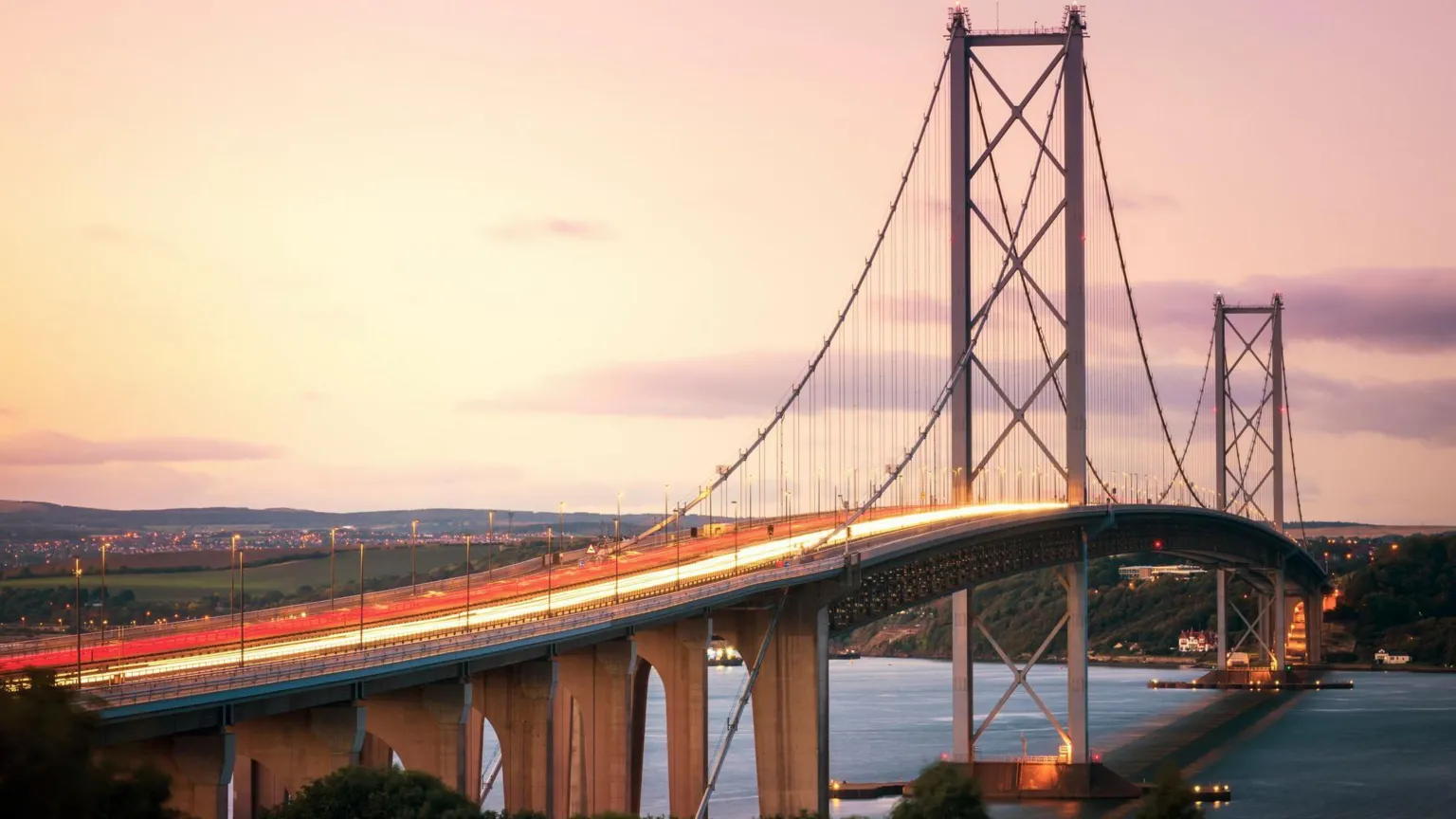  The Forth Road Bridge - a suspension bridge over the Firth of Forth - is seen at sunset with a long exposure showing red and white trails of lights from traffic in travelling in both directions.