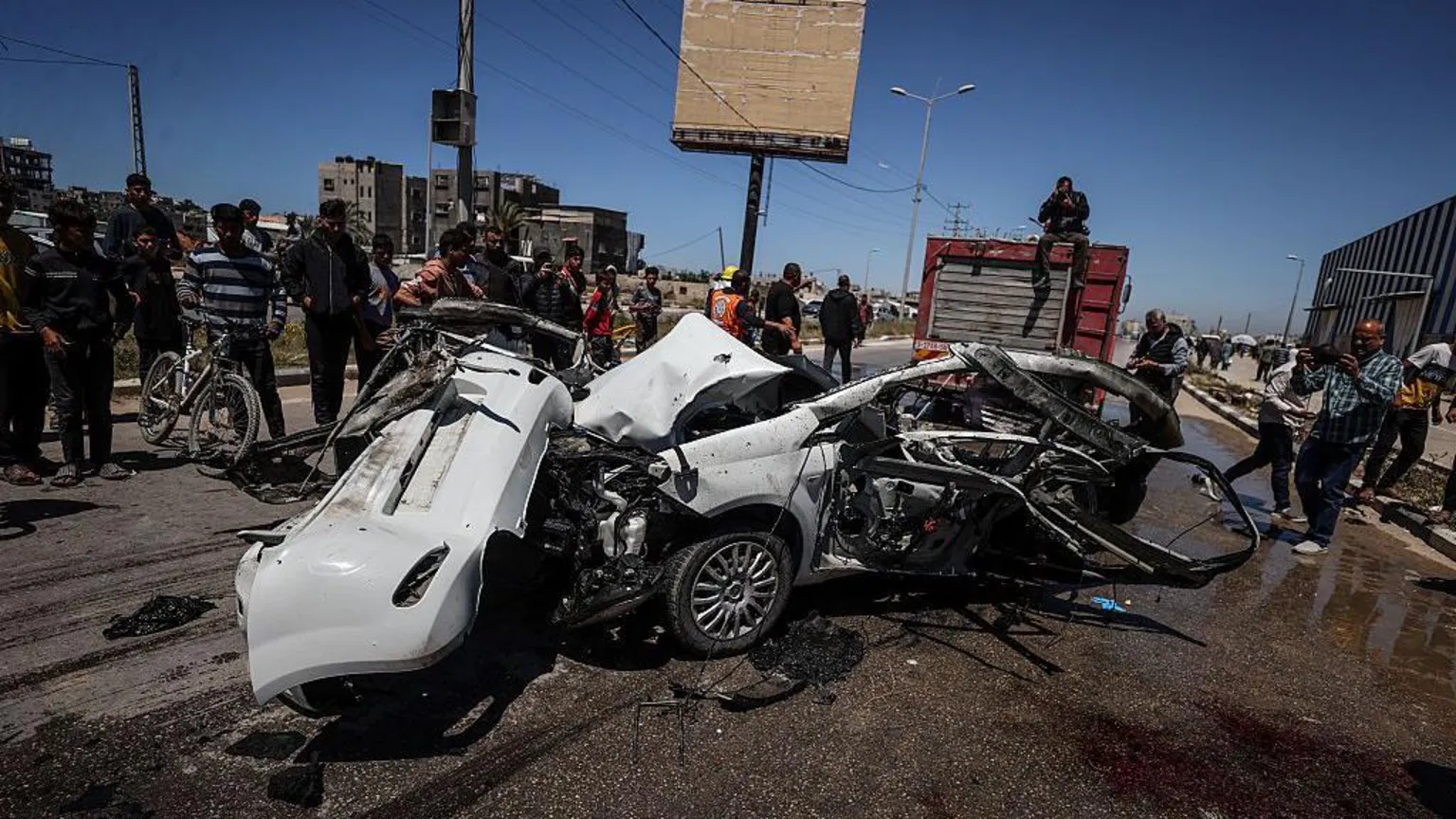Anadolu via Palestinian first responders and residents look at a car reportedly destroyed in an Israeli artillery strike that killed three people, in the Maghazi area of central Gaza (23 April 2026)
