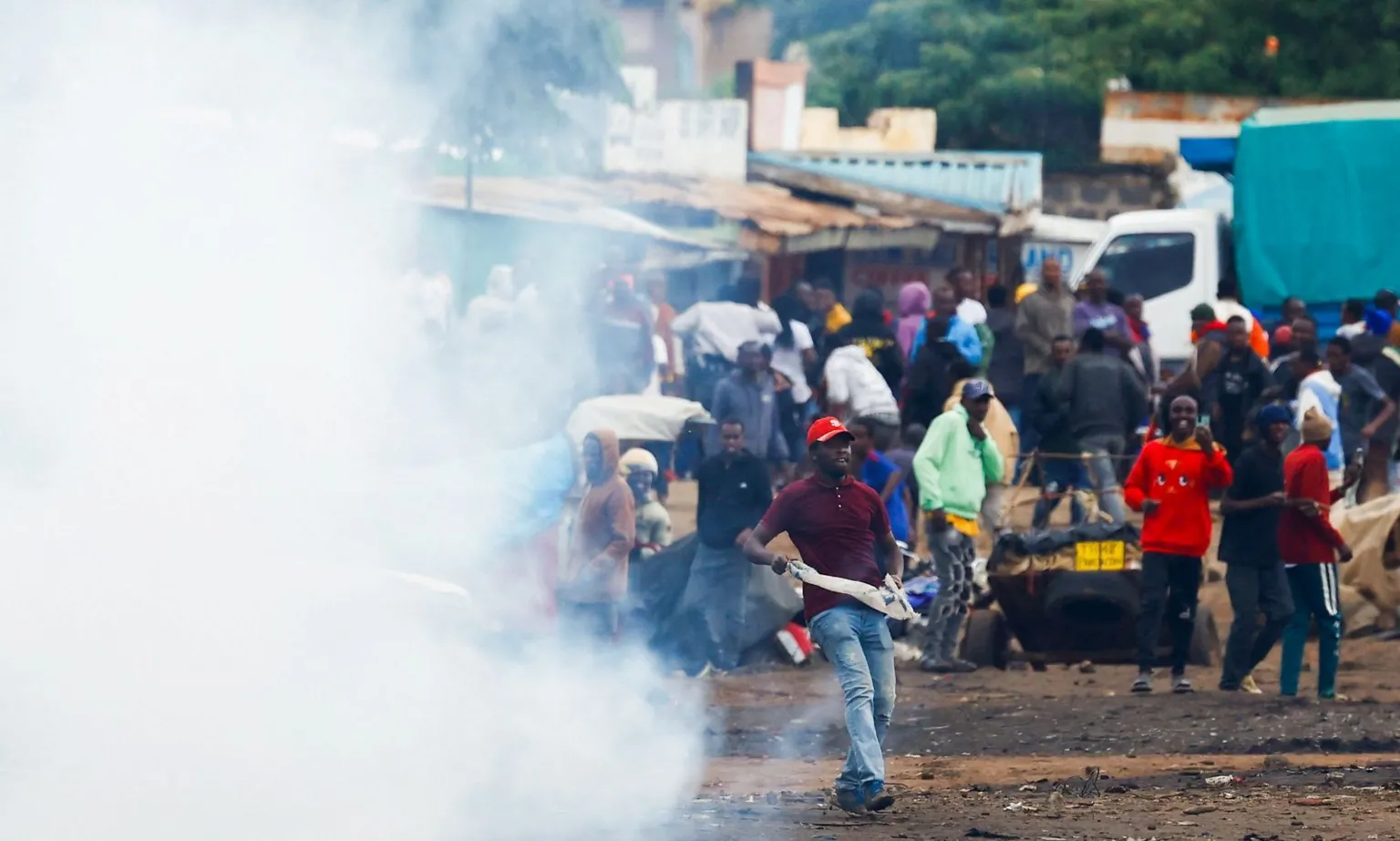  A protest scene in Tanzania with tear gas in the foreground and a crowd of people looking on