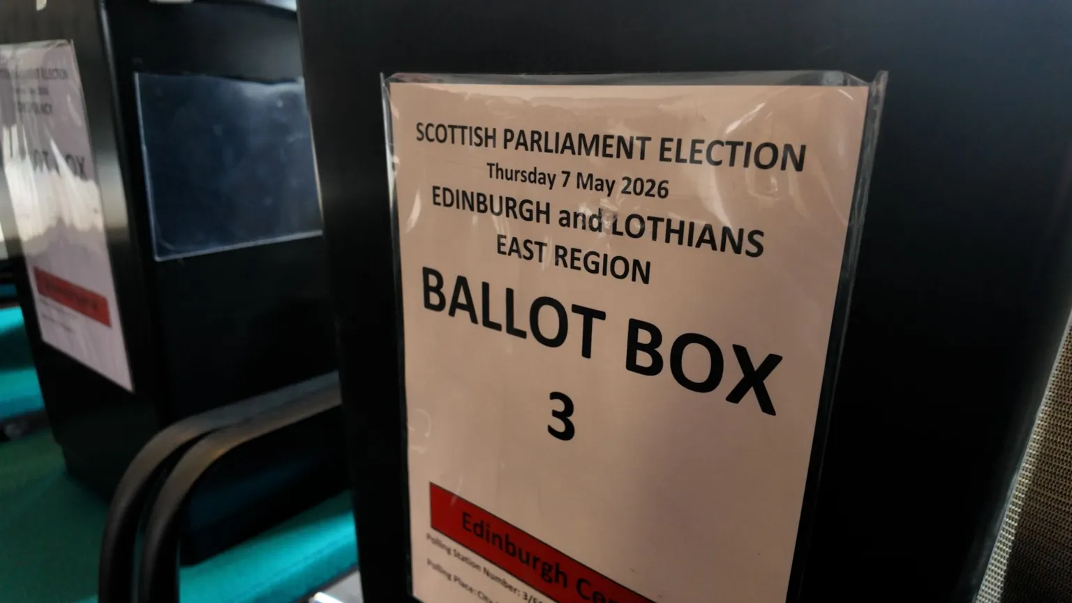A close-up image of a ballot box. It is a big black box with a white sign saying 