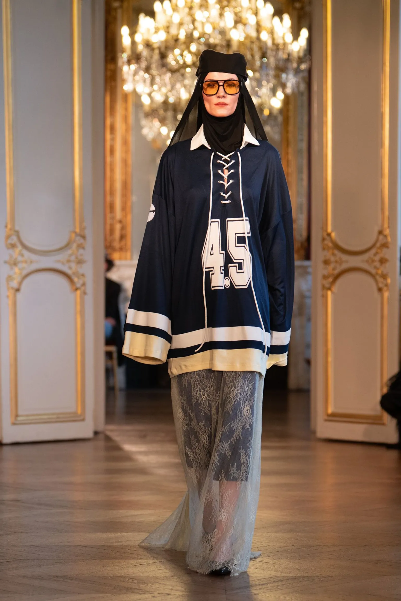 Rooful Ali A model wearing a long sporty jersey, skirt, headscarf, yellow-tinted sunglasses and cap