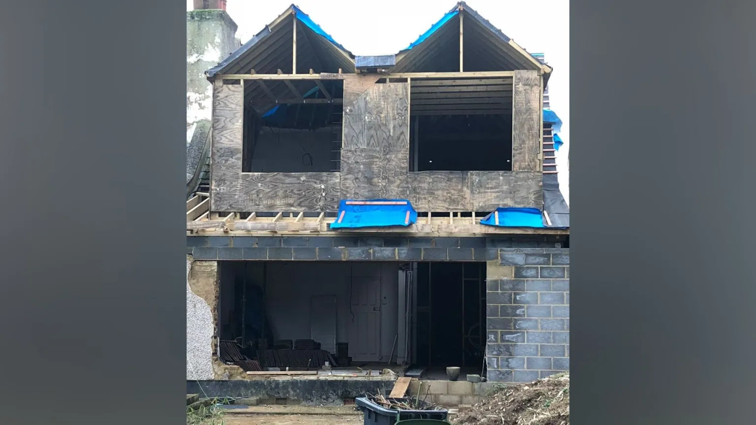 Nick Marns An extension to a two-storey house, which does not yet have any doors or windows. It is being held together by wooden beams.