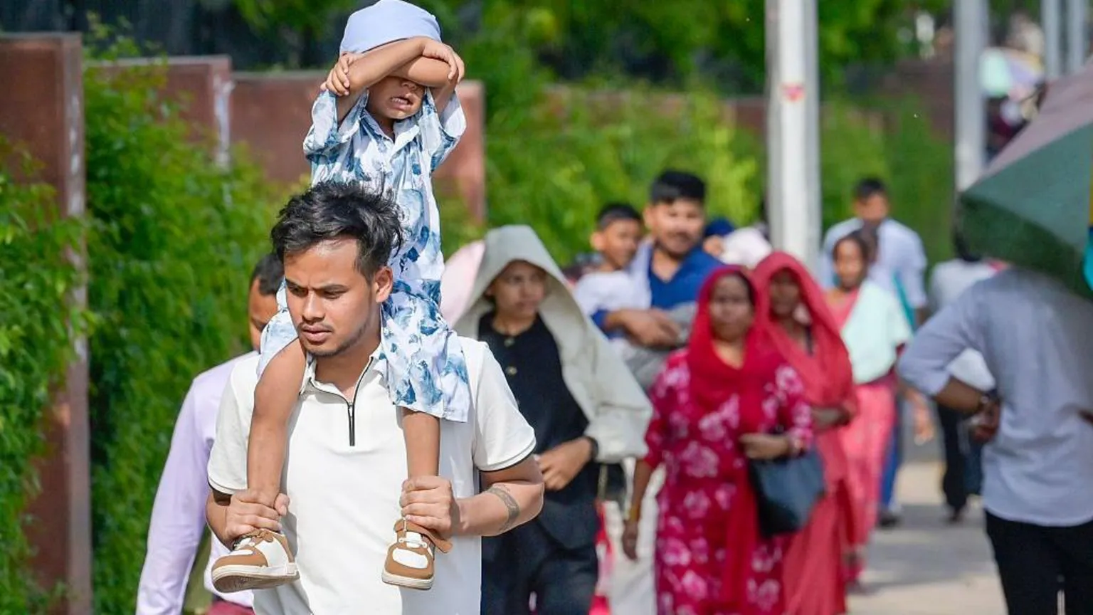  Visitors seen using umbrellas to protect themselves from sun on hot summer day outside Lotus temple, on April 17, 2026 in New Delhi, India.