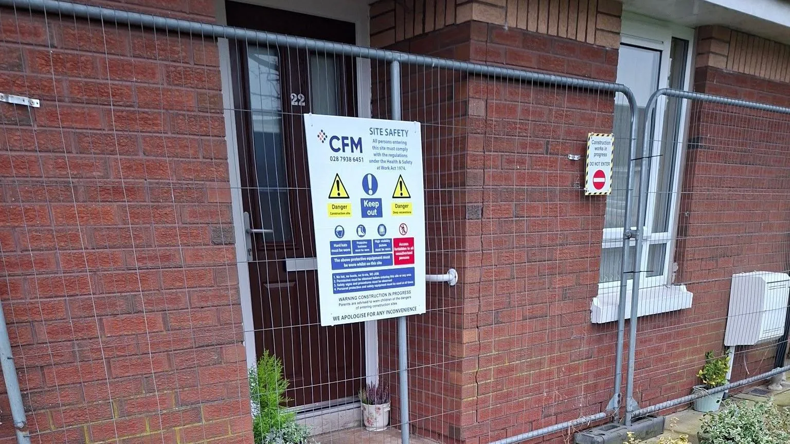 Thomas Kyle The front door to a red brick house which is blocked off by fencing. There is a saferty warning sign on the fence.