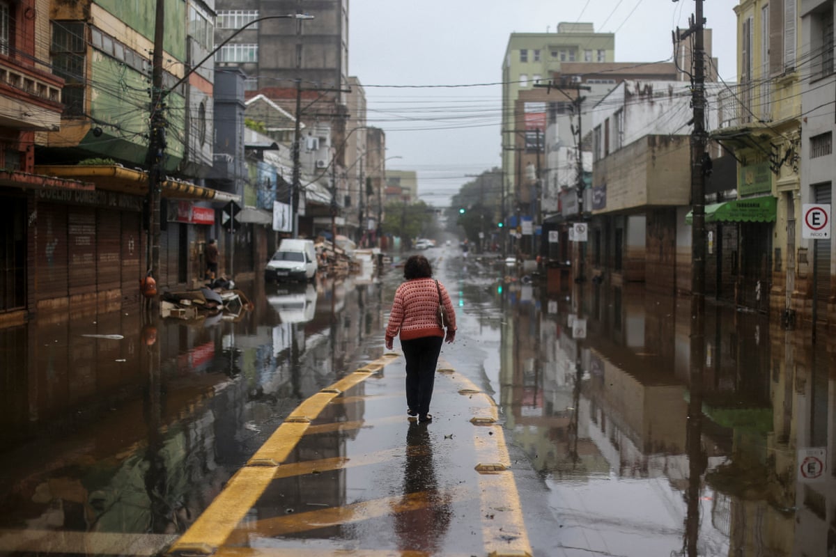 A woman walks along a flooded city street.