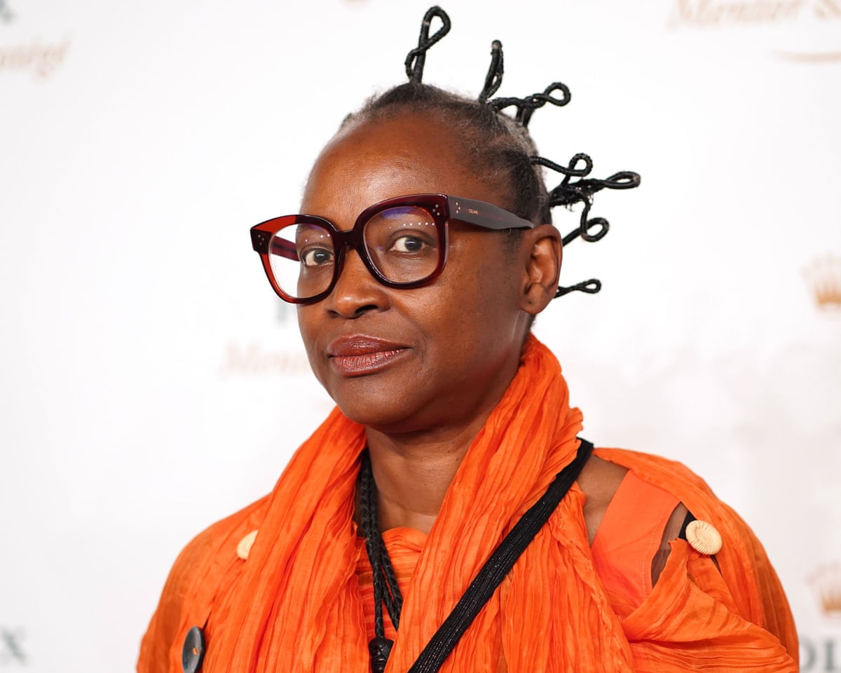 Koyo Kouoh in an orange jacket and glasses