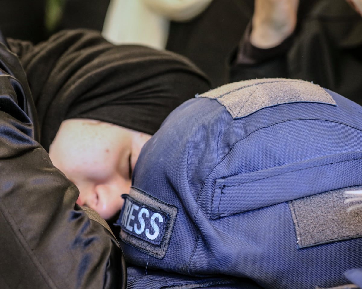 A woman mourns next to a press ballistic helmet as relatives and friends gather at the house of Amal Khalil.
