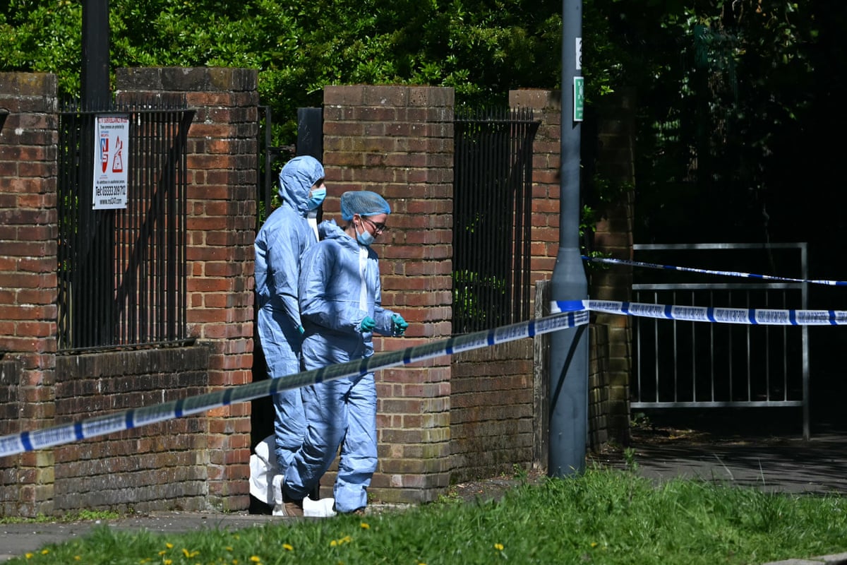 Forensic officers in protective suits cross a cordon at the scene of the synagogue arson attack