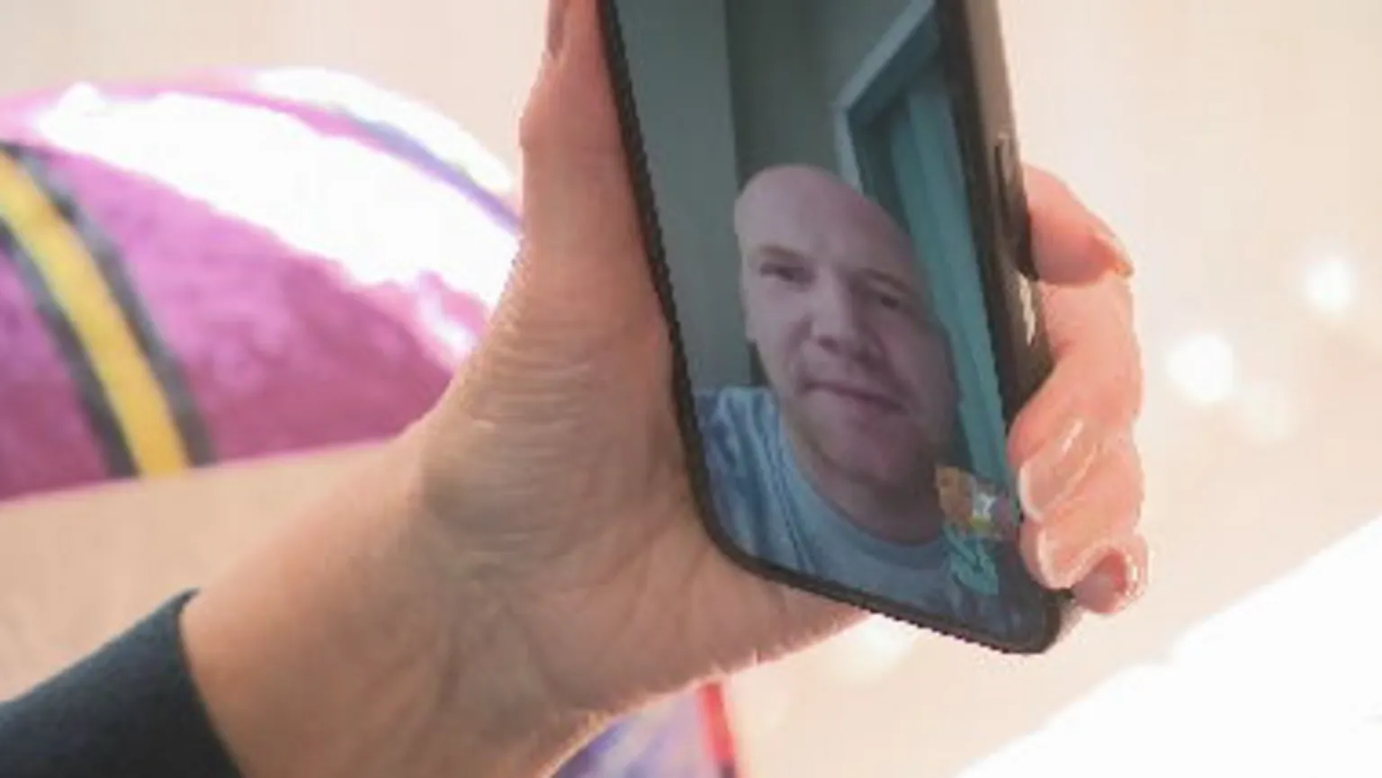 Helen's hand holding a phone during a face time call to her son