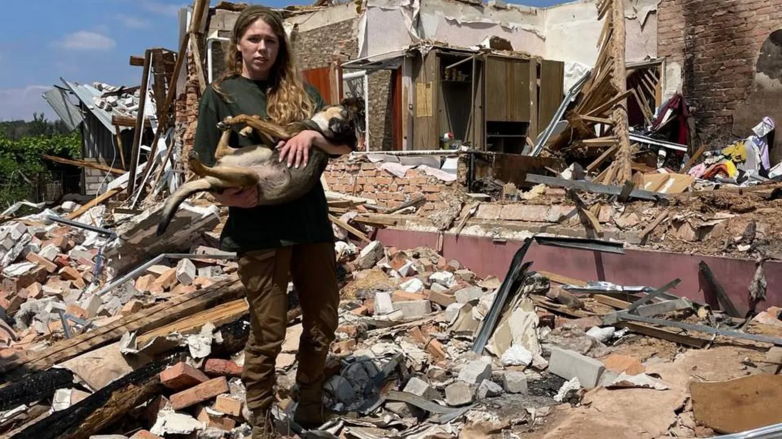 12 s A woman holds a dog in the rubble of a house