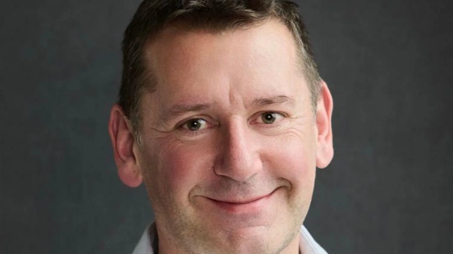 NAHT A man with short brown hair, smiling at the camera. 