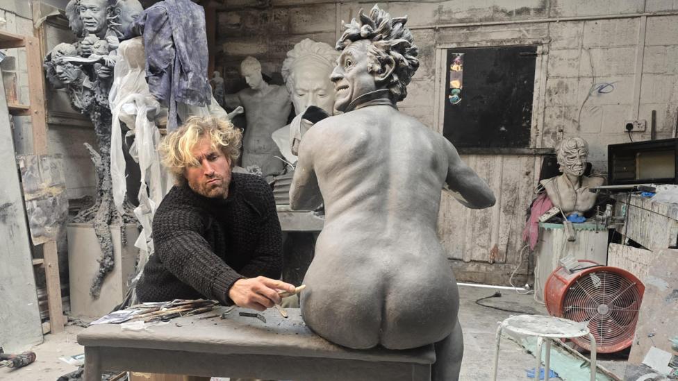 Llun y cerflun gyda'r cerflunydd Nick Elphick