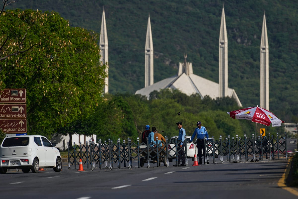 Police officers stand guard at a checkpoint near Faisal Mosque, in background, for the US and Iran talks, in Islamabad