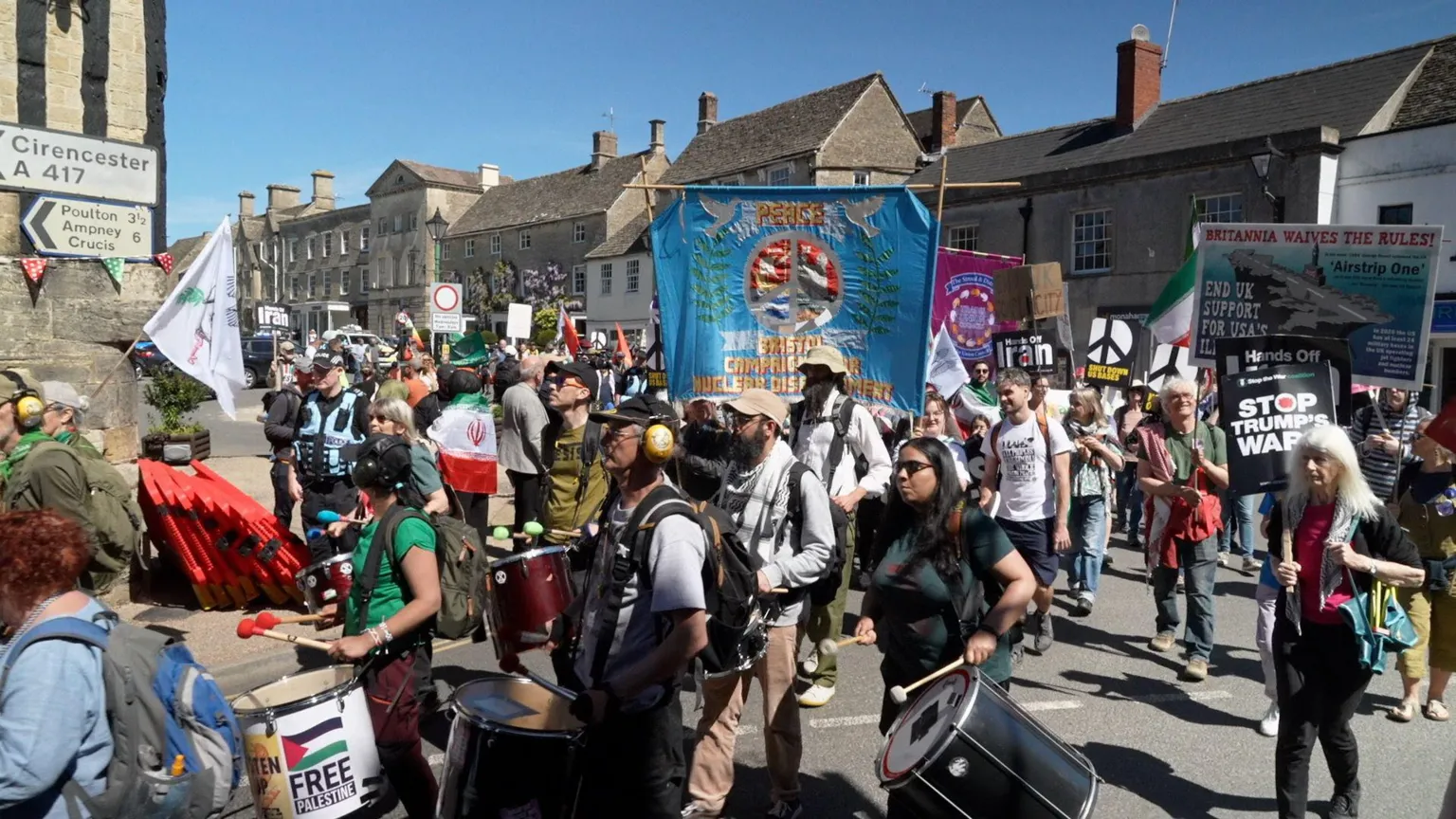 People have gathered on a street in a protest, holding flags and placards.
