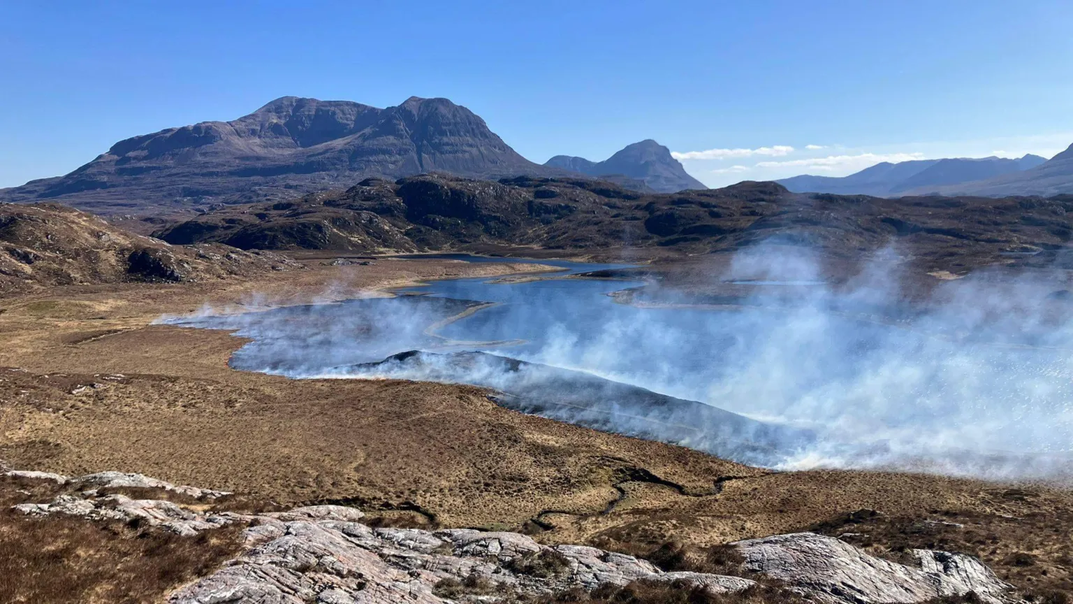 The Assynt Foundation A mountain landscape with clouds of smoke in the distance 