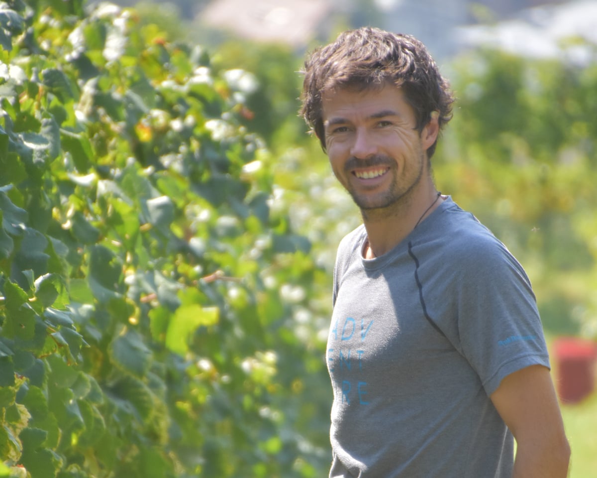 Konrad smiling broadly, in a T-shirt in his sunny vineyard