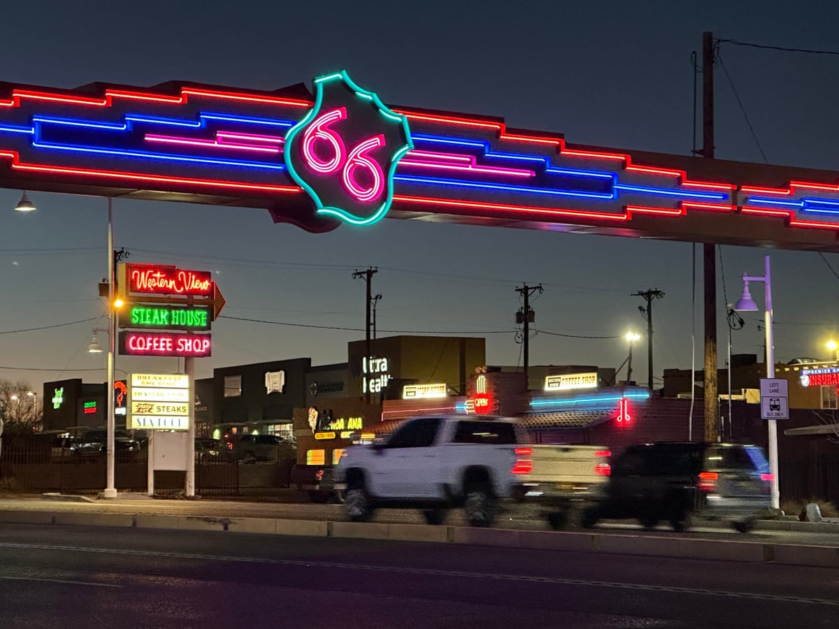 Traffic passes under a neon Route 66 sign over the road