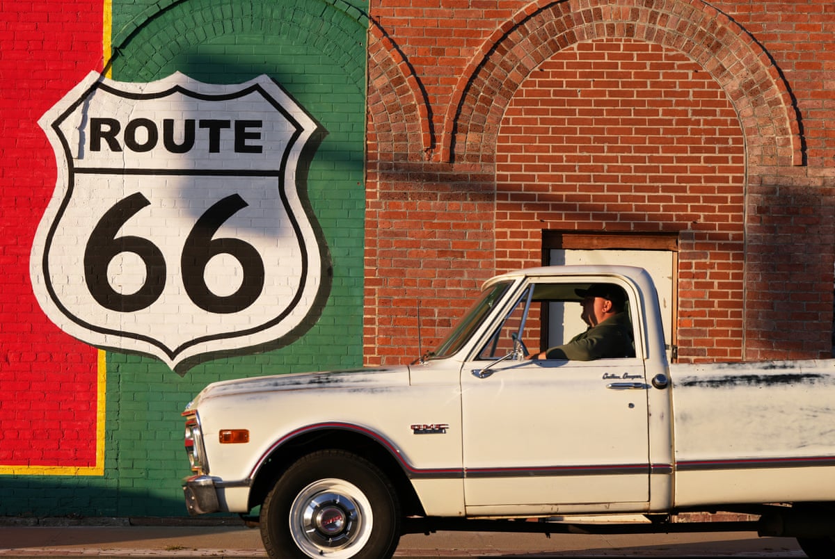 A motorist pulls up to a stop light in front of a Route 66 sign