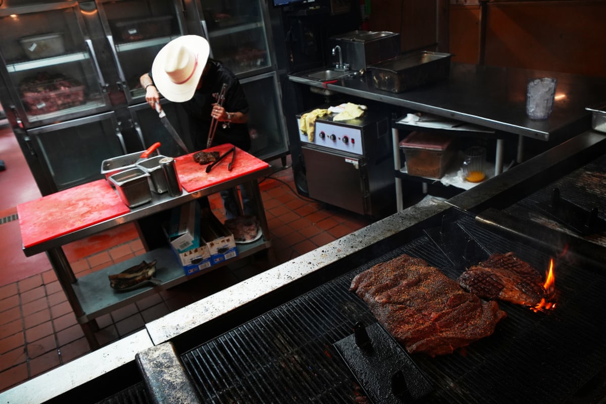 A cook wearing a stetson prepares a 72oz steak