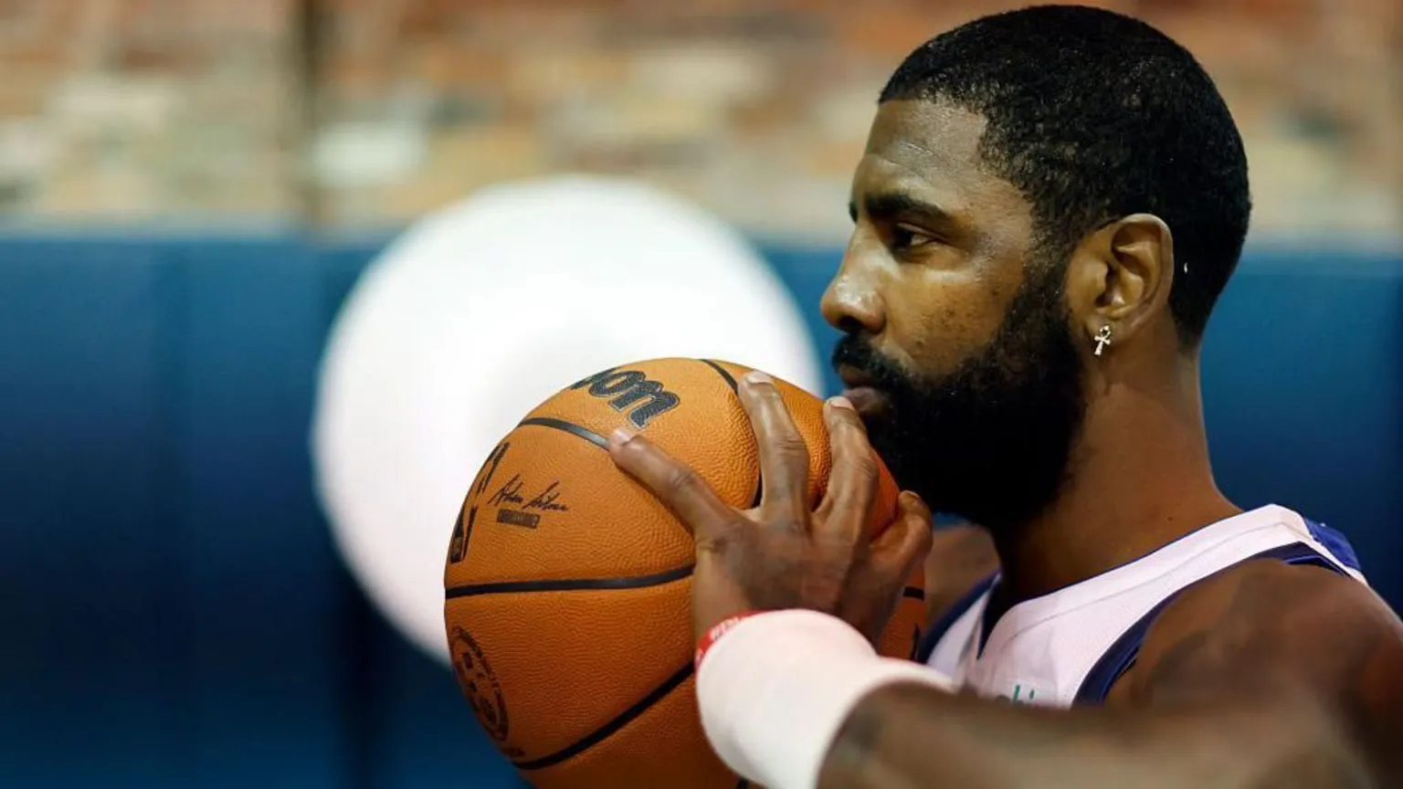  Kyrie Irving holding a Wilson-branded basketball to his chin.