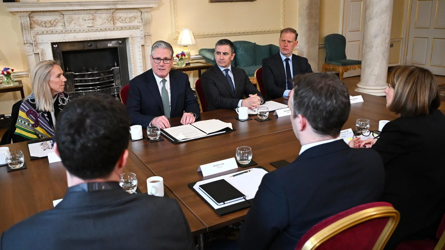  Sir Keir Starmer speaks at meeting with six other people as they sit around a table in a room at 10 Downing Street.