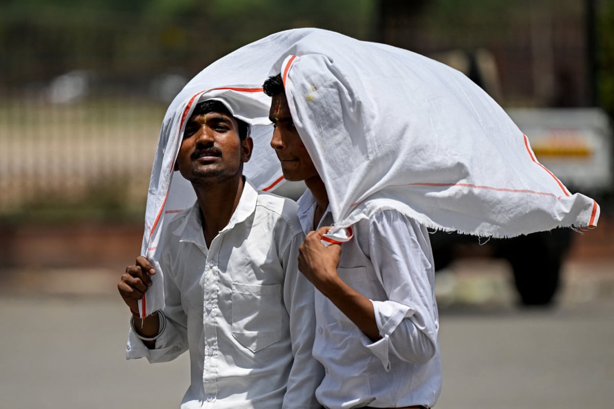 Two men wearing white shirts carry a white sheet over their heads as they walk around