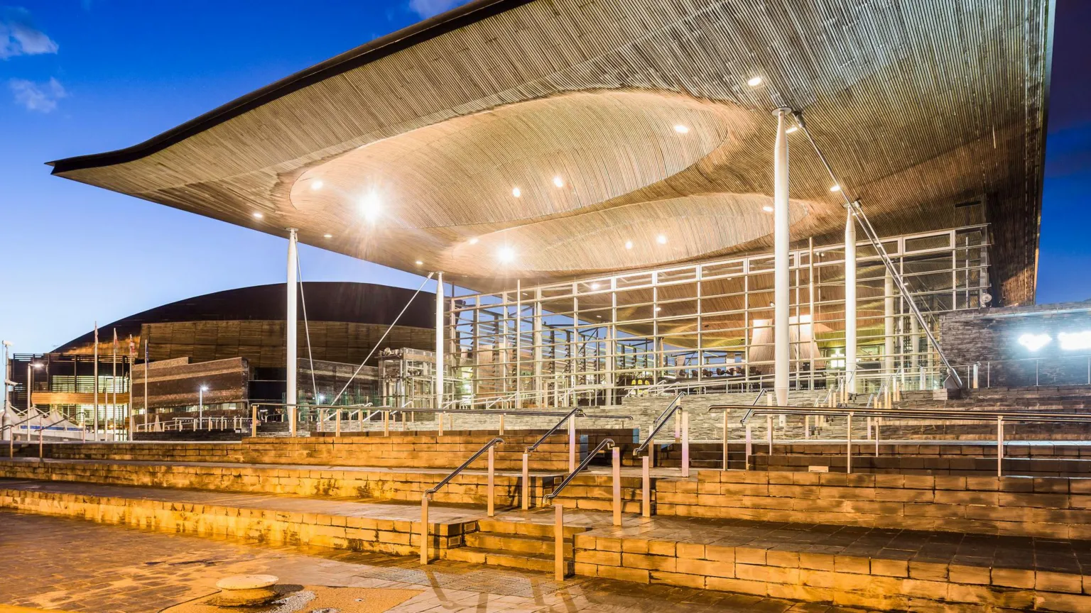  A view of the Senedd building. Designed by architect Richard Rogers, the building’s sweeping roof, slate plinth, internal funnel and glass walls were created to rise out of Cardiff Bay and welcome visitors in.