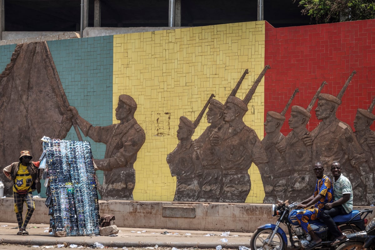 A motorcyclist rides past a monument in support of the Malian army in Bamako