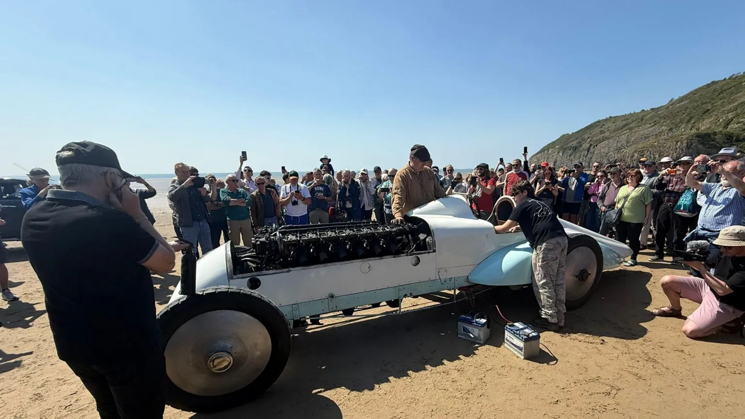 A general view of the car 'Babs' with a crowd of spectators behind it. It is white and light blue. 