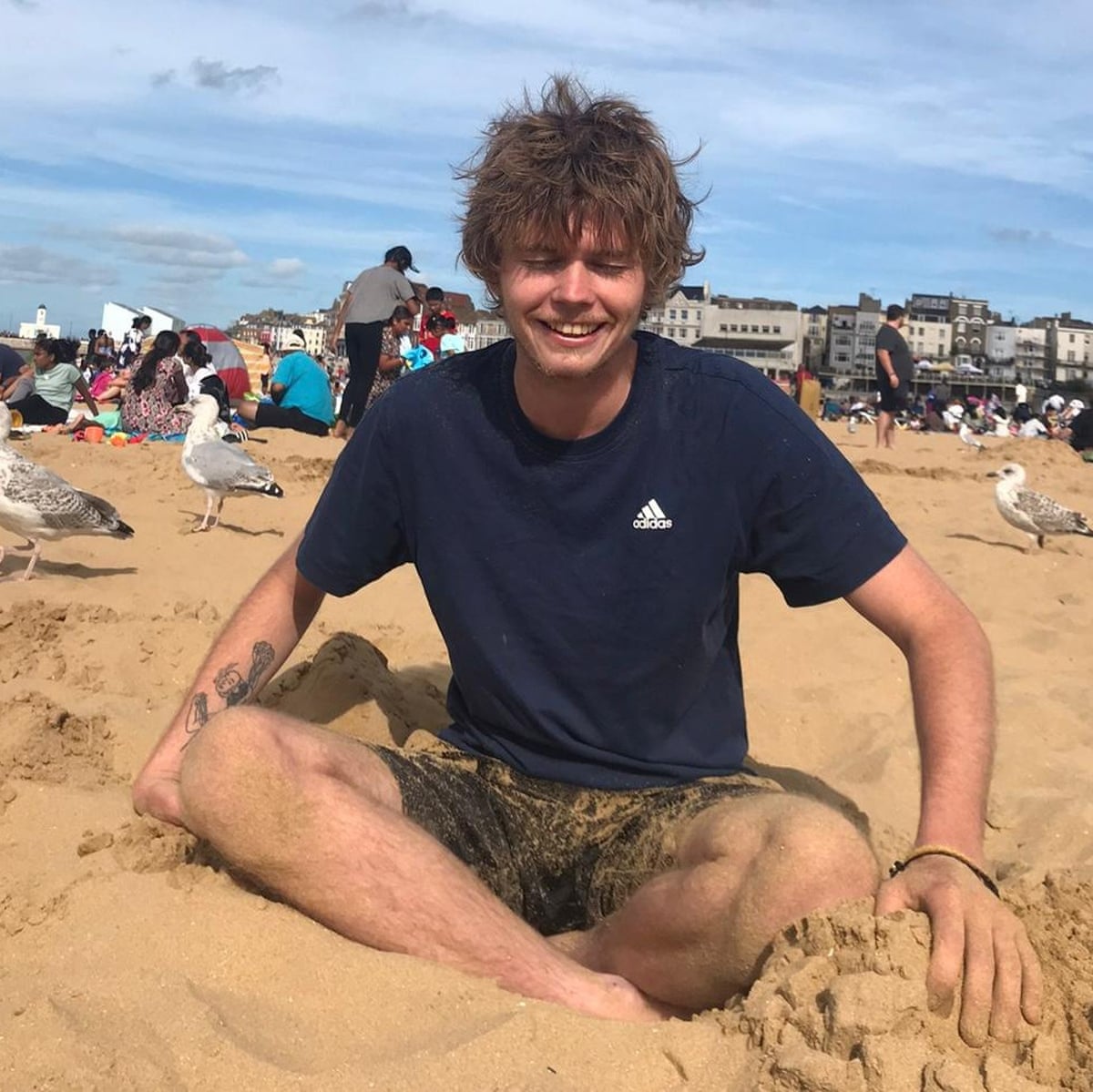Crow Tricks sits on a beach in front of some gulls
