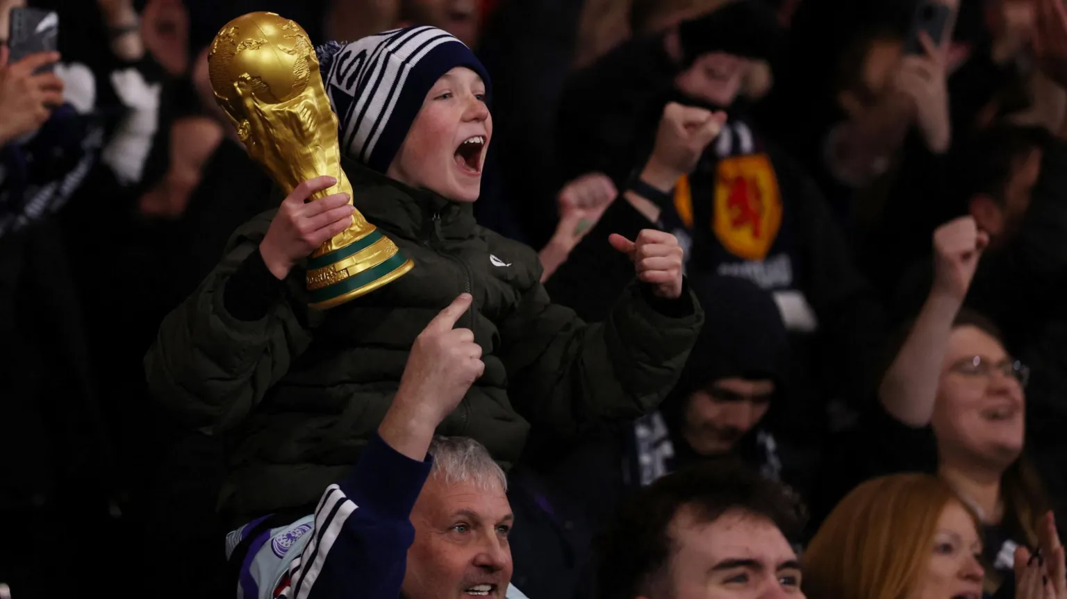  A young Scotland fan holding a replica World Cup trophy celebrates with other supports Scotland's 4-2 win over Denmark at Hampden.