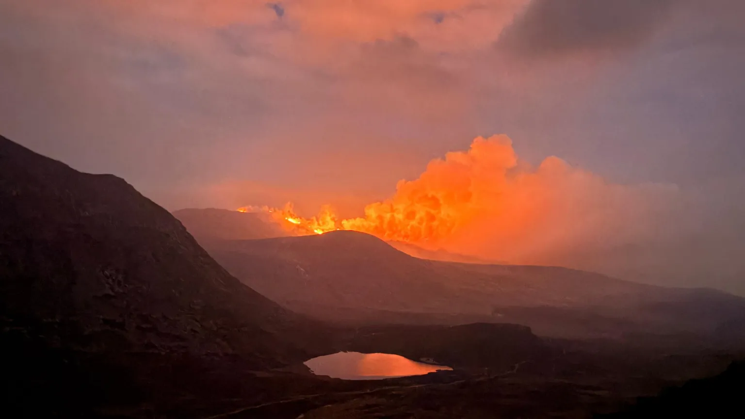 Caleb Emerson Orange smoke rising from the top of a mountain. 