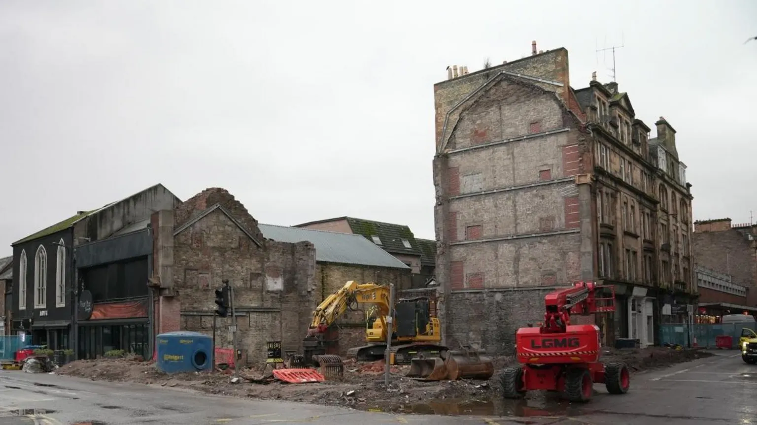 The site of a major fire in Perth, now completely cleared. There is a view of a road and a large space where the building used to be. There is an intact building next to the site and diggers.