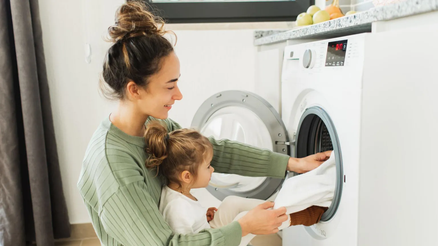  Mother and child girl little helper loading washing machine