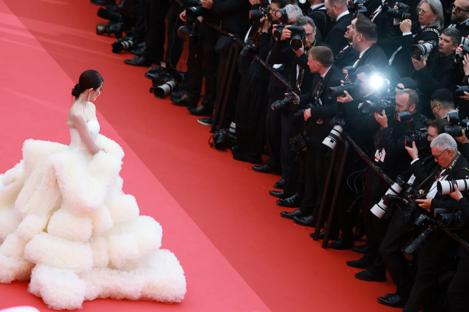 EPA An actress in an elaborate voluminous white dress on the Cannes red carpet facing a bank of photographers in black tie.