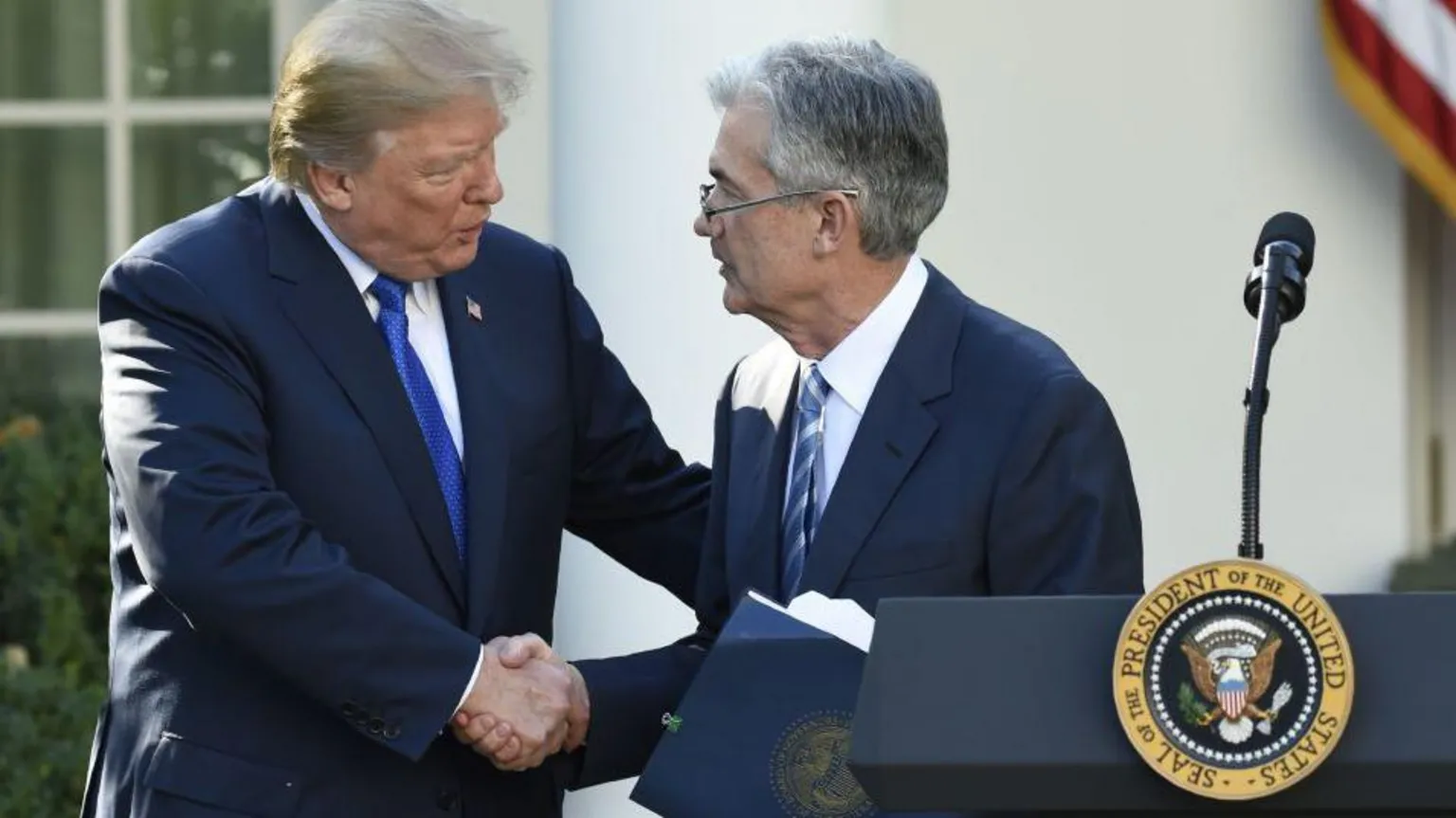  US President Donald Trump, wearing a dark blue suit, white shirt and electric blue tie, shakes hands with his nominee for chairman of the Federal Reserve, Jerome Powell. He wears a dark blue suit, a white shirt and a blue and silver tie. 