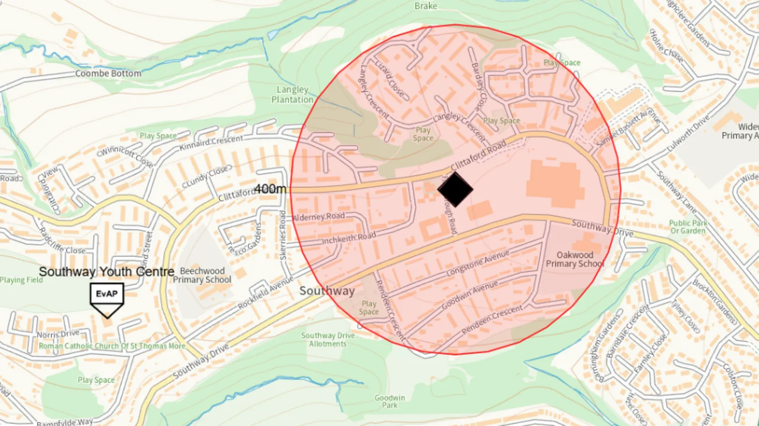 Plymouth City Council A map showing a residential area with streets, housing blocks, schools, and green spaces clearly marked. At the centre is a white diamond symbol. Around that point is a large shaded circular area, coloured in light red and orange tones, indicating a defined radius or zone of interest.