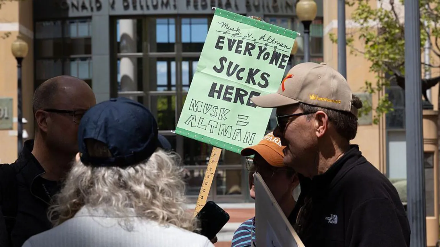 Getty A group of four people gathered outside a building. One is holding a green sign which reads 