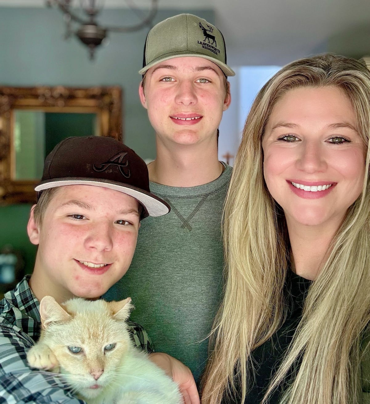 a mother and her two sons smile while holding their cat