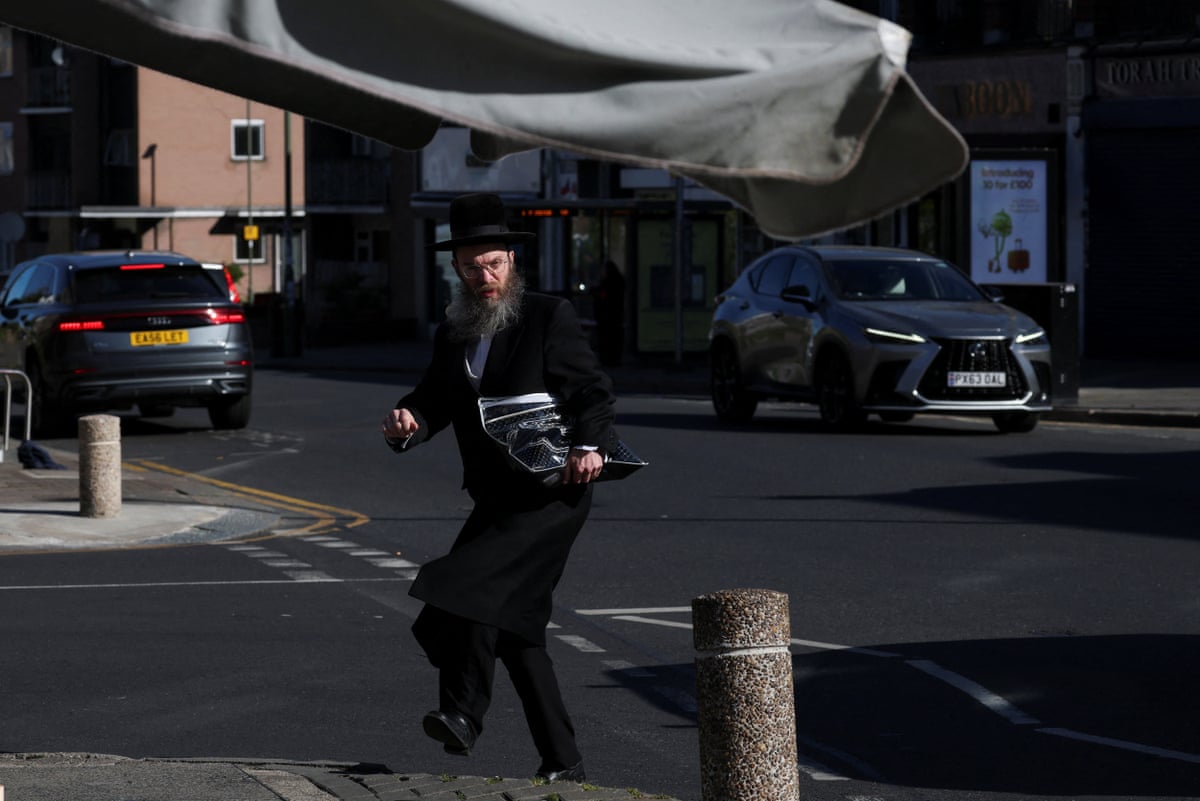 An Orthodox Jewish man walks near the scene where a man was arrested following a stabbing.