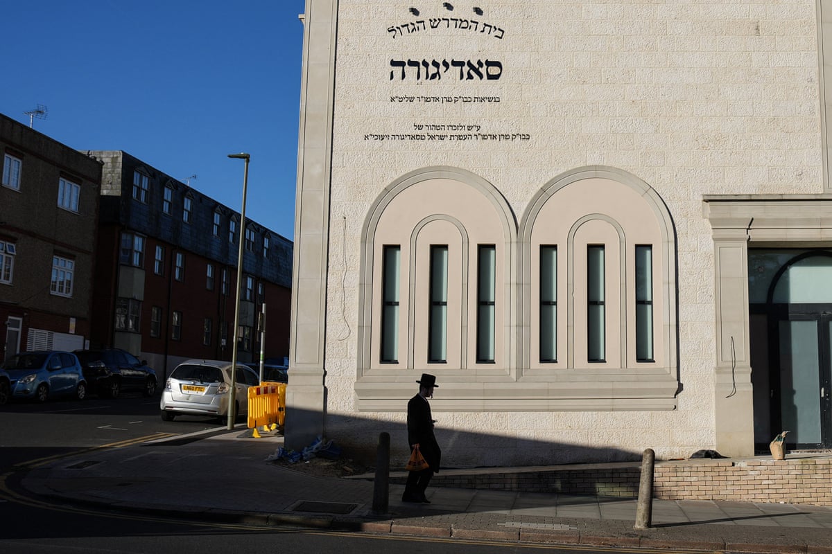 A Jewish man walks past a synagogue.