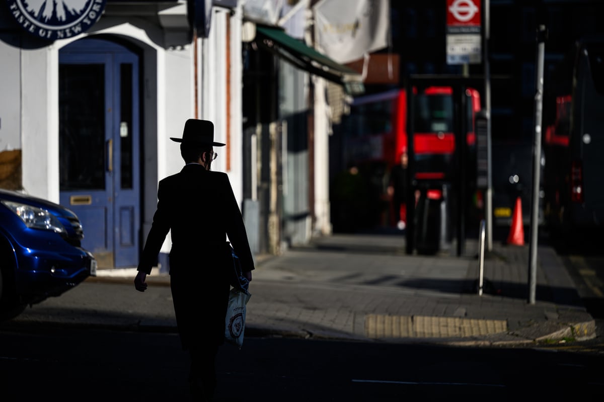 An Orthodox Jew walks towards the bus stop where a man was attacked in Golders Green.