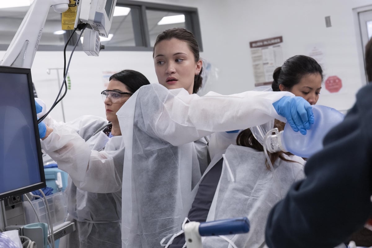 A doctor in hospital scrubs looking after a patient
