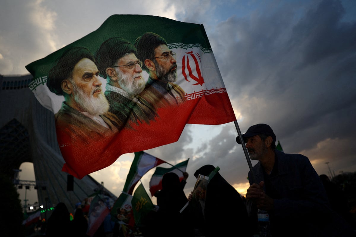 A man holds a flag with a picture of late leader of the Islamic Revolution Ayatollah Ruhollah Khomeini, late Supreme Leader of Iran Ayatollah Ali Khamenei and Iran’s new Supreme Leader Mojtaba Khamenei, during a rally in Tehran, Iran, April 29, 2026.