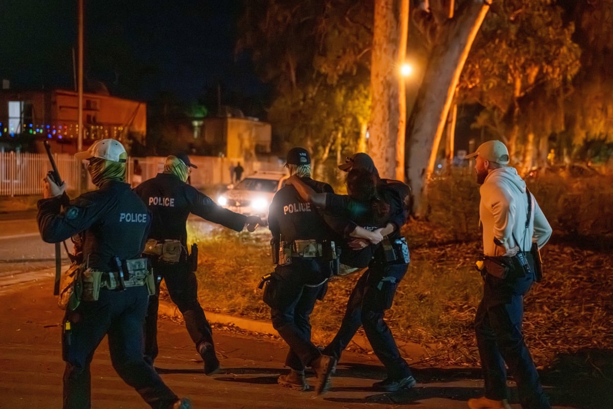 A woman is carried by police during clashes between community members and law enforcement outside Alice Springs hospital on Thursday night.