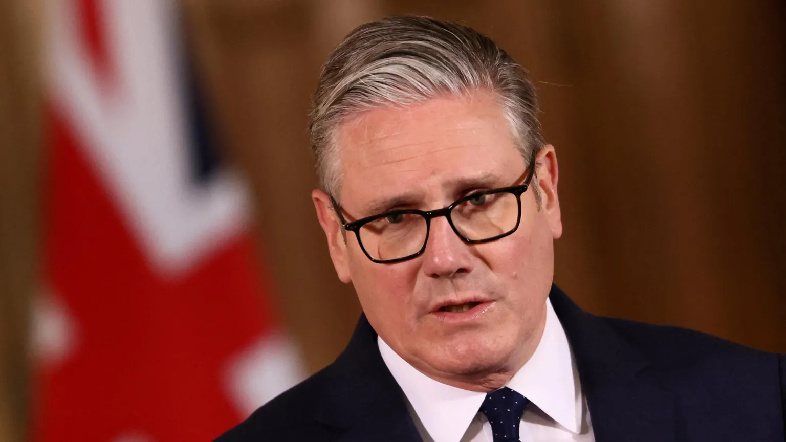  Sir Keir Starmer in a dark suit and tie at a Downing Street press conference, with Union flag backdrop