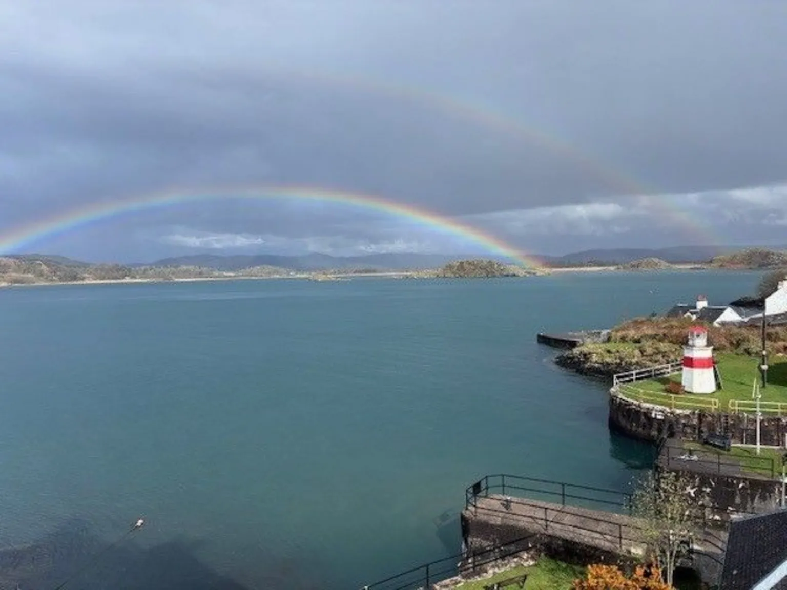 Mary Whyte A double rainbow over the sea. A lighthouse and pier is on the right. 