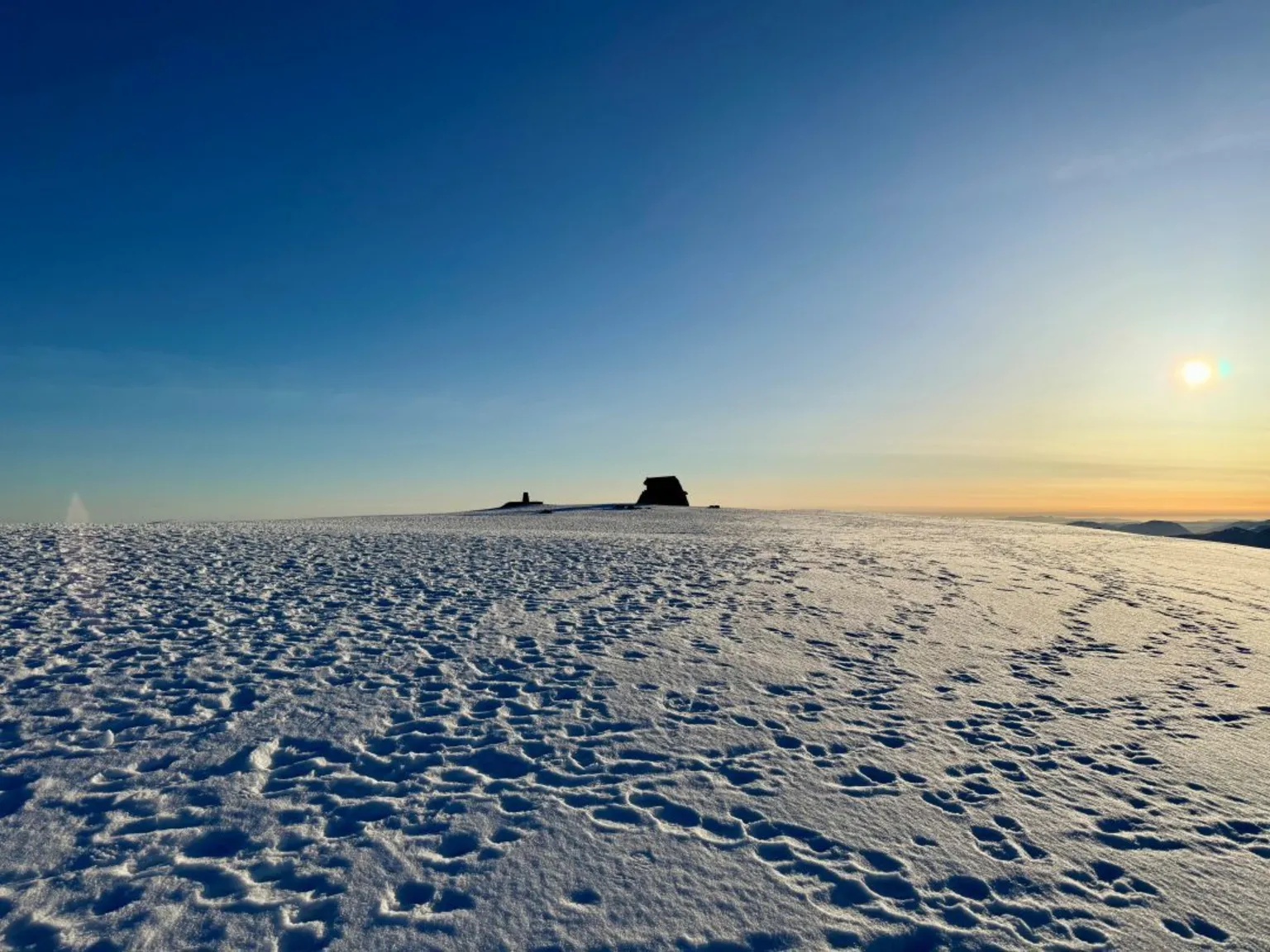 Bill Cameron Blue sky with a yellow sunrise and snow covered summit of Ben Nevis. 